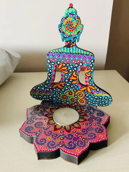 A beautiful Buddha candle holder in shades of teal and magenta, with intricate dot work and patterns that glow beautifully by candlelight.