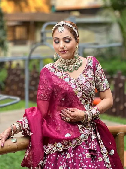 A close-up focusing on the flawless makeup and the beautiful contrast between the magenta outfit and the green stones in the jewellery.