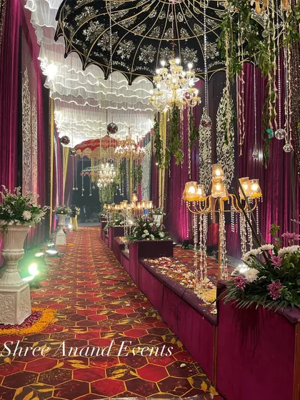An opulent walkway featuring plush velvet seating, ornate candelabras, and intricately designed umbrellas hanging from the ceiling.