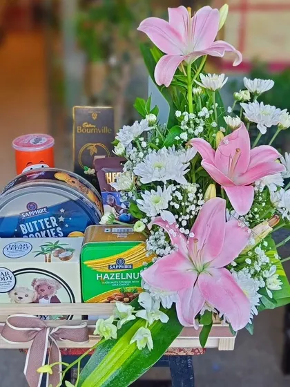 A simple yet beautiful hamper featuring a striking arrangement of pink lilies and white chrysanthemums. It's combined with a selection of cookies and chocolates for a thoughtful gesture.