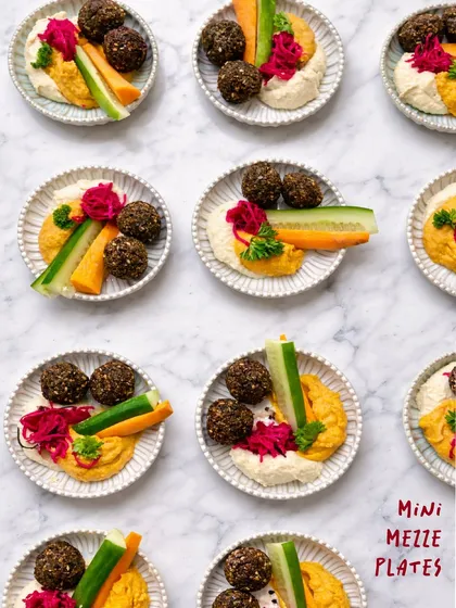 For intimate gatherings, I offer these mini mezze platters. Each individual plate is a stylish alternative to a large grazing table, featuring smoked piri-piri hummus, Mediterranean hummus, crispy falafels, and fresh veggie sticks. It's a personal and elegant way to serve your guests.