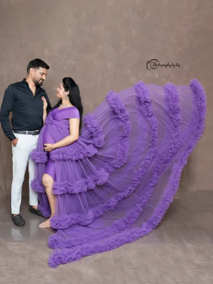 A glamorous studio shot of a couple with a flowing purple ruffled gown. The dramatic lighting and pose create a high-fashion feel.