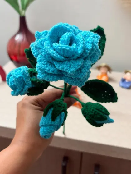 A close-up look at the detailed petals of a hand-crocheted blue rose, showing the intricate stitch work that goes into creating these everlasting blooms.