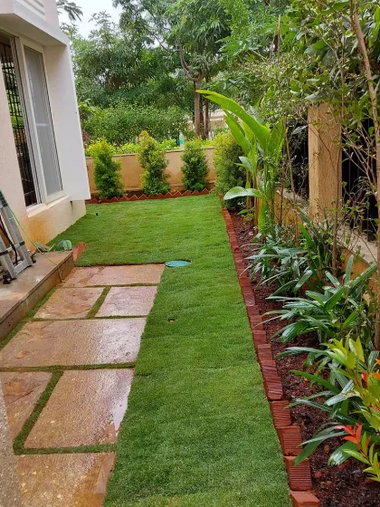 A side yard transformation in progress, showing freshly laid turf next to a new stone path and planting bed. This demonstrates the key stages of a garden installation.