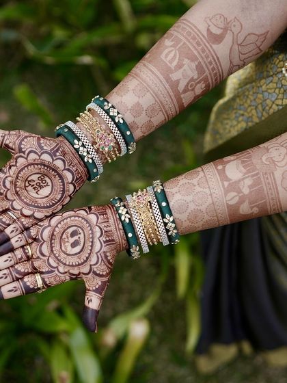 A complete view of a baby shower mehendi with a "Boy or Girl?" theme. The design also includes a baby face motif and is complemented by the client's beautiful green bangles.