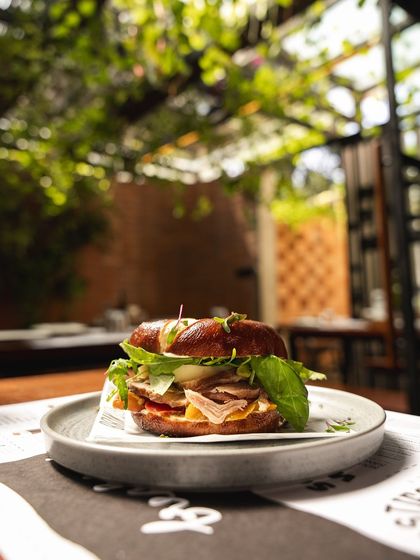 The Smoke Ham Bagel Sandwich in all its glory, pictured in our green outdoor seating area.