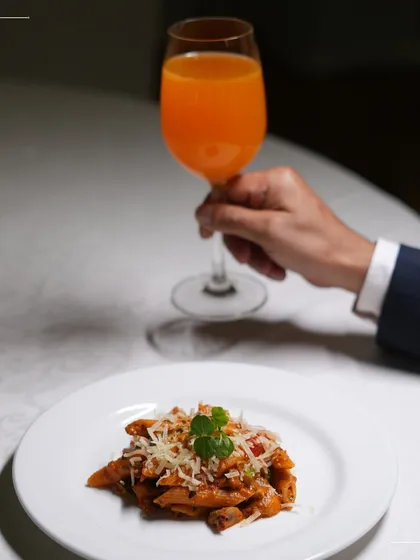 A simple yet elegant plate of penne pasta, paired with a refreshing drink. This image represents our ability to deliver high quality, delicious food for corporate lunches and daytime events.