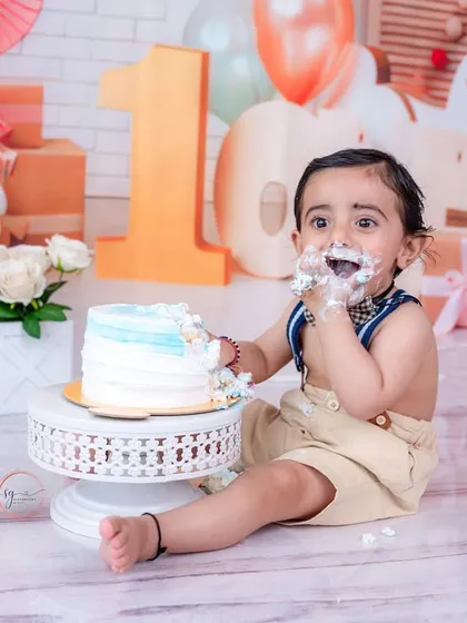 A wide shot of the cake smash setup, showing the birthday boy enjoying his cake with a festive backdrop of gifts and a rocking horse.