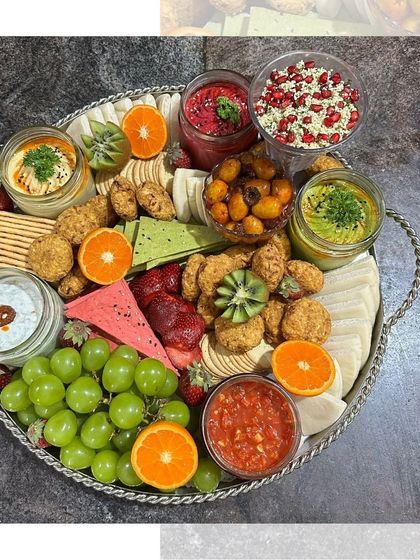 A vibrant and fresh Mezze platter featuring multiple dips, falafel, fresh fruits like grapes and strawberries, and a variety of crackers. It's a healthy and delicious option for any party.