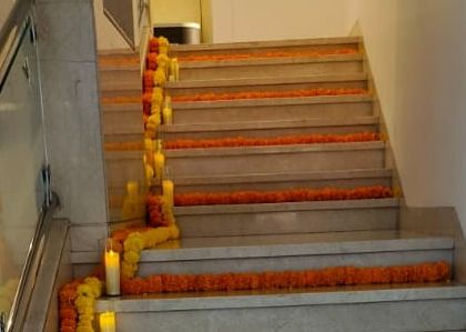 We believe in decorating every part of the venue. Here, we've adorned a staircase with garlands of yellow and orange marigolds and placed flameless candles to guide guests and extend the festive Haldi theme.