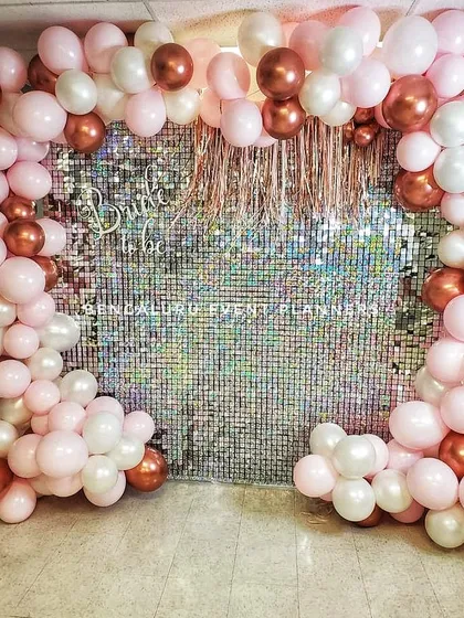 I created this chic 'Bride to be' photo booth with a sparkling silver shimmer wall. The wall is framed by a custom balloon arch in a stylish palette of pink, white, and rose gold, making it a perfect spot for bridal shower pictures.