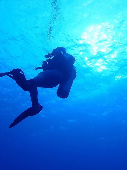 A serene silhouette of a diver gliding through the deep blue waters of Lakshadweep.