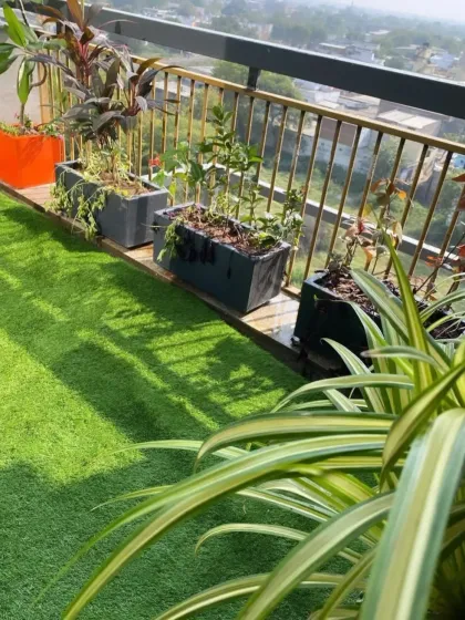 A close-up shot from a balcony makeover, focusing on the rich texture of the artificial grass and the healthy plants in their modern planters. This highlights the quality materials we use to create a lasting and beautiful finish.