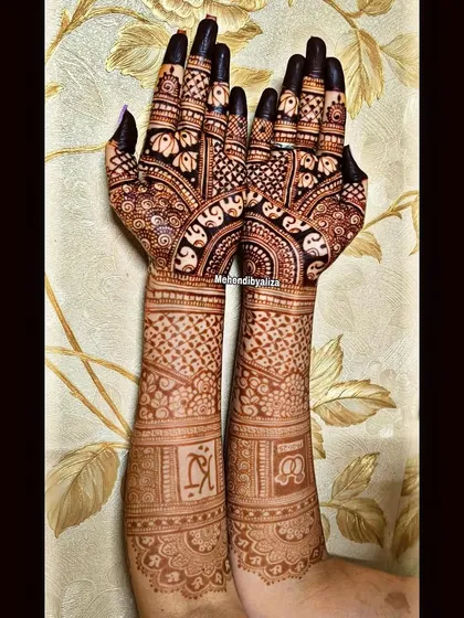 The beauty of a maturing henna stain on a full bridal design. The initials of the couple are subtly woven into the pattern on the arms.