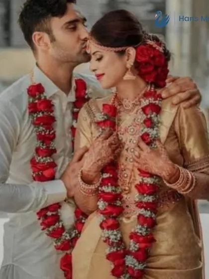 A tender moment as the groom kisses his bride's forehead. The red rose Varmalas add a classic and romantic touch to their wedding attire.
