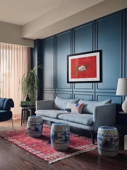 This family room was designed around the client's love for the color blue and antique ceramics. I used deep blue wall panelling to create a cozy, enveloping feel, juxtaposed with a vibrant red rug and the client's personal collection of blue and white pottery.