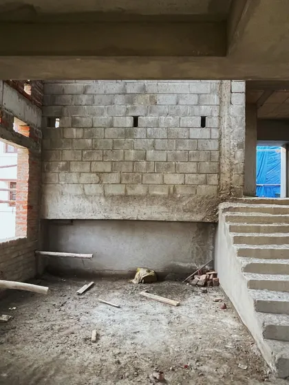 The interior of the house at an early construction stage. The image shows the concrete staircase and blockwork walls, forming the base for the future split-level living spaces.