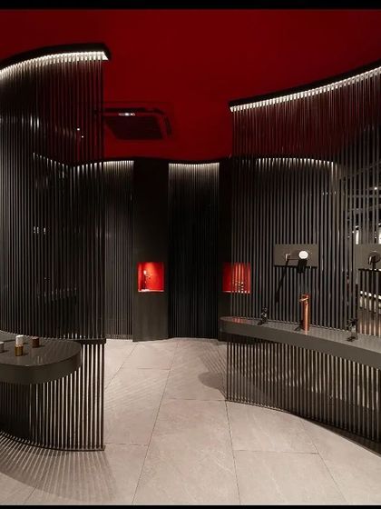In the Fima showroom, the lighting is designed to be dramatic and bold. I used concealed linear lights to trace the curves of the slatted walls, creating a captivating play of light and shadow that draws customers in. The vibrant red ceiling is intentionally left dark to enhance the moody, focused atmosphere.