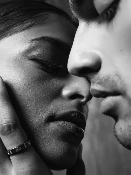 An intimate black and white close-up. Removing color allows the viewer to focus on the subtleties of the moment: the texture of the skin, the slight parting of the lips, and the feeling of closeness between two people.
