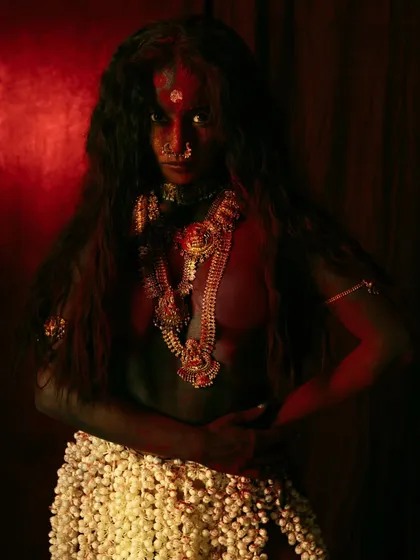 This frame from the 'Kali' series uses deep shadows and a direct, confrontational gaze to capture the goddess's untamable spirit. The focus is on the raw emotion conveyed through the eyes and posture.