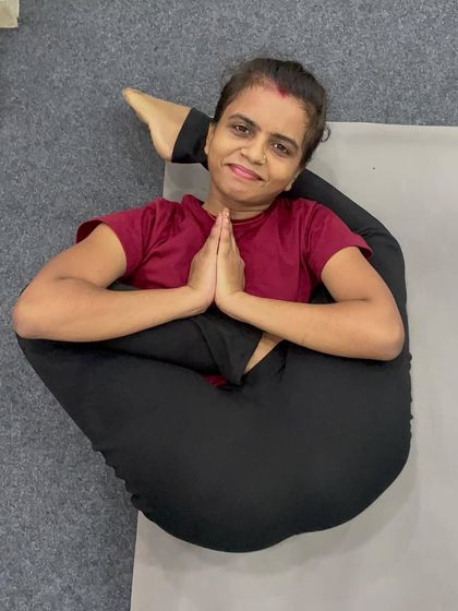 A student smiles while holding a challenging posture where both legs are wrapped around the body, a testament to the joy found in advanced practice.