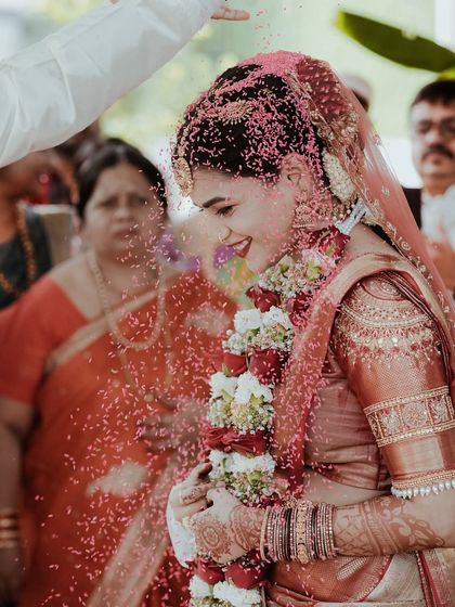A shower of pink petals rains down on the bride during her ceremony. This photo freezes the motion and captures her serene smile amidst the celebration.