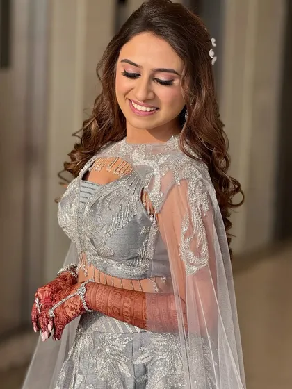A vision in silver for her sangeet night. This look features highly defined, glittery eyes and a soft lip, letting the eyes do all the talking. The sleek hair completes this modern and chic look.