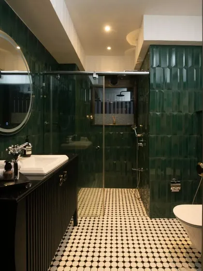 The master bathroom in this home is a moody masterpiece, wrapped in emerald green beveled tiles. The black and white patterned floor and classic fixtures create a vintage-inspired yet modern feel.