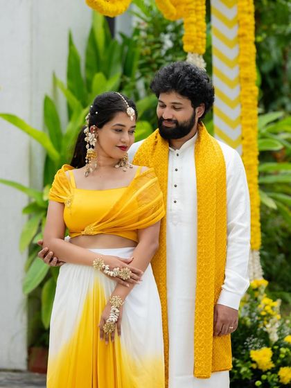 A happy couple posing together. The vibrant yellow in both their outfits creates a cheerful and coordinated look, ideal for a Haldi ceremony or festive celebration.