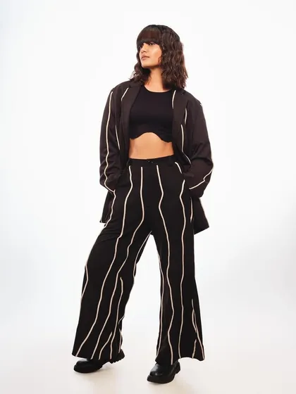 A full-length shot for Schwarzkopf's "Beatniks" trend. The makeup is minimal and modern, with a focus on clean skin, which supports the edgy, textured hairstyle and monochrome outfit.
