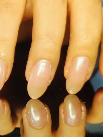 A clean and natural look with a sheer, glossy pink polish on beautifully shaped almond nails.