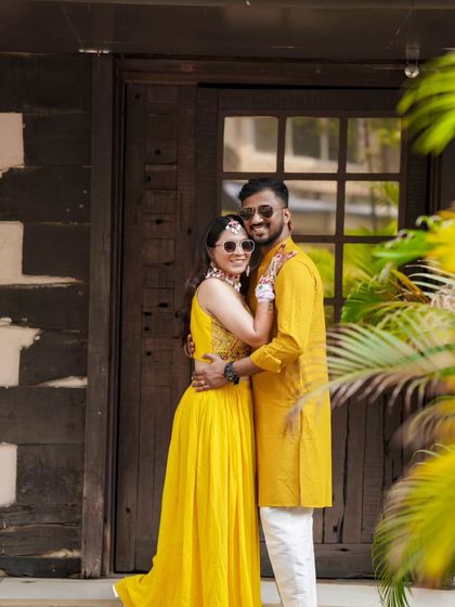A fun and stylish couple portrait from a Haldi ceremony, with the couple wearing matching sunglasses.