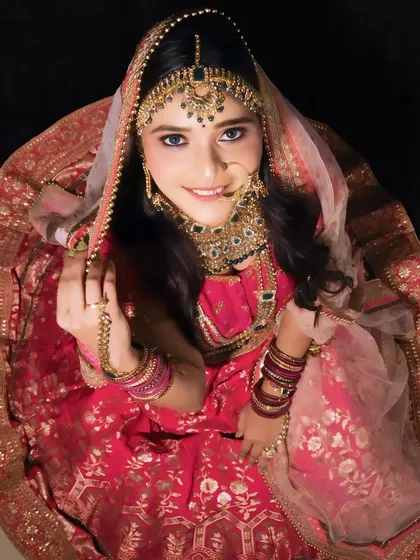 An artistic top-down shot of a bride in her full lehenga and jewelry. This showcases the complete look, from the intricate *matha patti* to the flow of the dupatta.