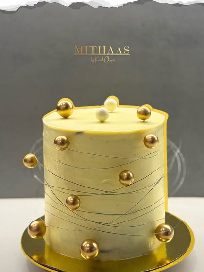 What does the world's dreamiest cake look like? For me, it's this tall, elegant creation with a pale yellow frosting, fine chocolate string work, and floating golden spheres.