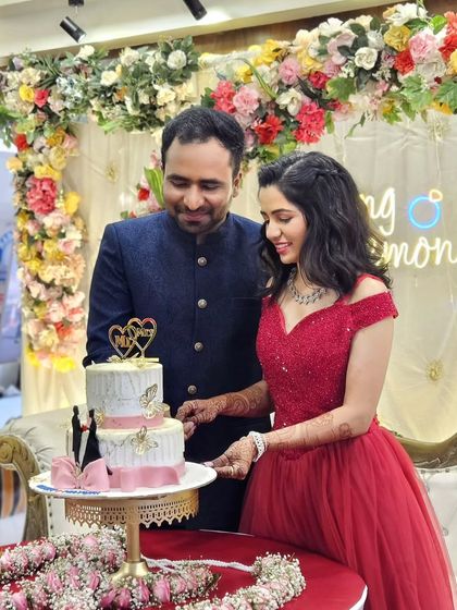 Celebrating their union with cake and smiles. The bride looks radiant in my off-shoulder red gown, a popular rental choice for engagement ceremonies.