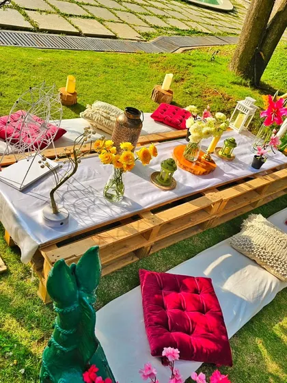 A closer look at the colorful poolside picnic table. The details include bright yellow flowers, pink cushions, and unique decorative pieces, showcasing a fun and eclectic style.