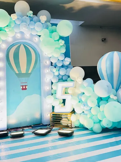 A hot air balloon themed party for a fifth birthday. The setup includes a large light-up number '5' and a balloon cascade that looks like clouds.