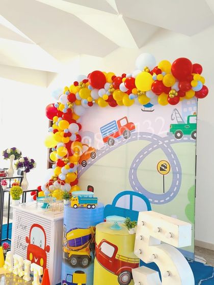 This construction and car theme is perfect for little vehicle lovers, featuring a custom backdrop with a winding road and colorful balloon arch.