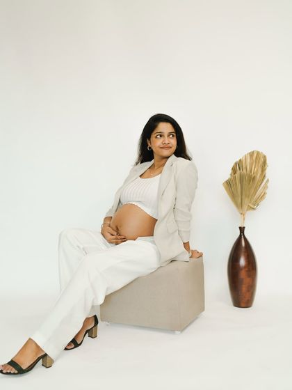 A chic and modern solo portrait. The white blazer suit creates a powerful yet graceful look, perfect for a stylish studio maternity session.