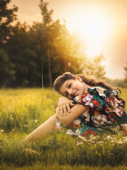 A serene portrait of an older girl sitting in a field of wildflowers at sunset. My outdoor kids' photography sessions are suitable for children of all ages.
