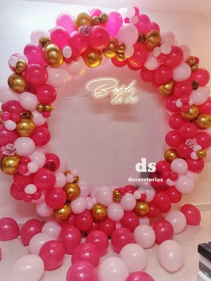 This full-ring balloon backdrop is one of our most requested items for bridal showers. We created this look with a vibrant mix of pink, white, and gold balloons, centered around a custom 'Bride to be' neon sign for the perfect photo opportunity.