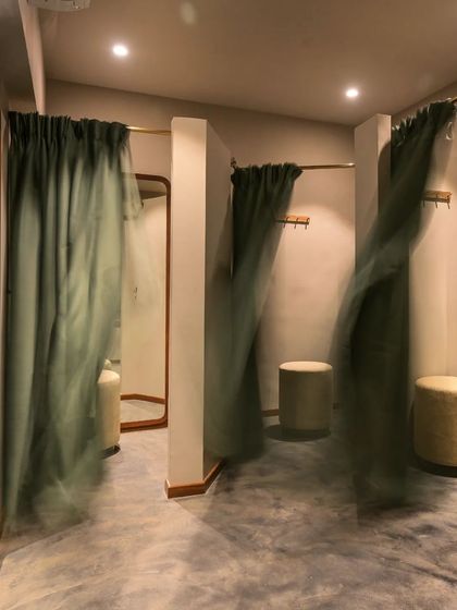 The fitting rooms at Bombay Shirt Company, featuring soft, flowing curtains and warm lighting to create a comfortable and private space.