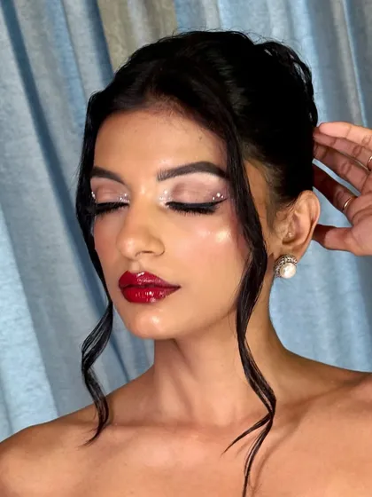 A close-up of the glossy red lip and shimmery, jeweled eye makeup. This is luxury glam at its finest.