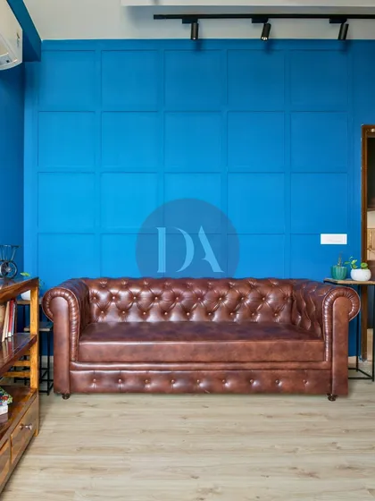 We love to play with color to reflect your personality. This bold blue accent wall, featuring classic paneling, creates a dramatic yet sophisticated backdrop for a timeless leather Chesterfield sofa, showcasing how color can define a room's character.