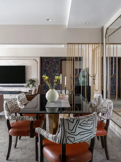 A modern-classic dining area. The chairs, with their leather seats and abstract print fabric, add an artistic flair, while the brass-legged glass table brings a touch of luxury.