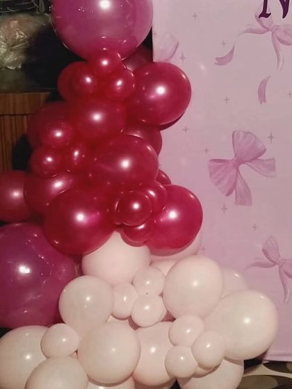 A close-up shot showing the detail of the balloon work, with a mix of deep pink and light pink balloons creating a rich, textured look against the custom-printed backdrop.
