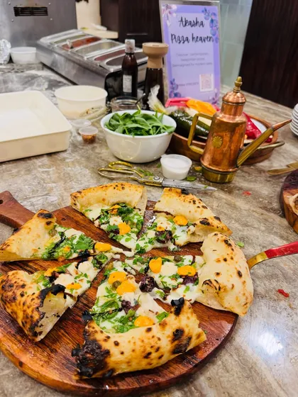 A unique white pizza with pesto, sliced mushrooms, and yellow cherry tomatoes, cut into slices and ready to be served at a private event.