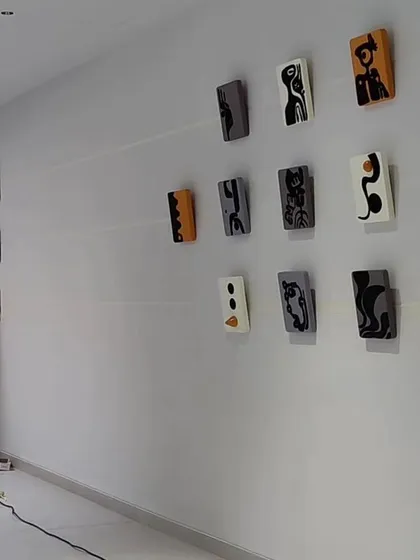 The artist carefully installing the small, individual panels of a large wall art installation in a Hyderabad residence.