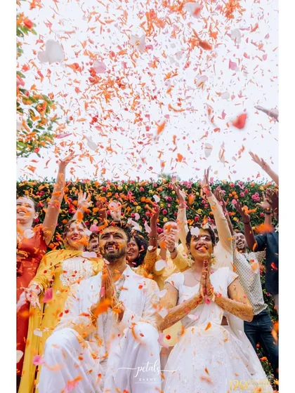 There is nothing more joyful than a shower of petals. For this Haldi, we created a moment of pure magic as the couple was blessed by friends and family under a rain of colorful flowers, set against a vibrant floral wall.