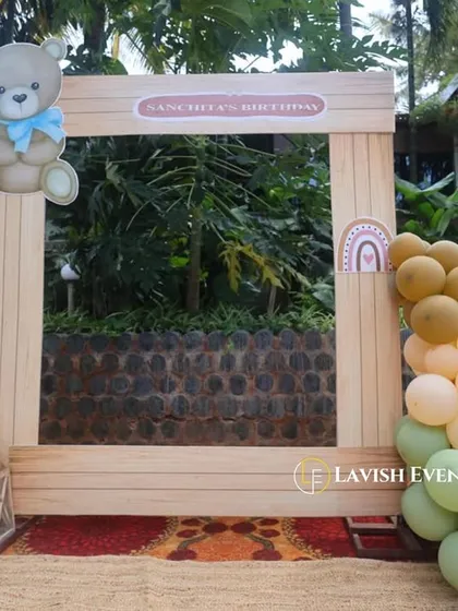 A custom wooden photo booth frame designed for a teddy bear themed party, complete with a cute bear cutout and a matching balloon garland.